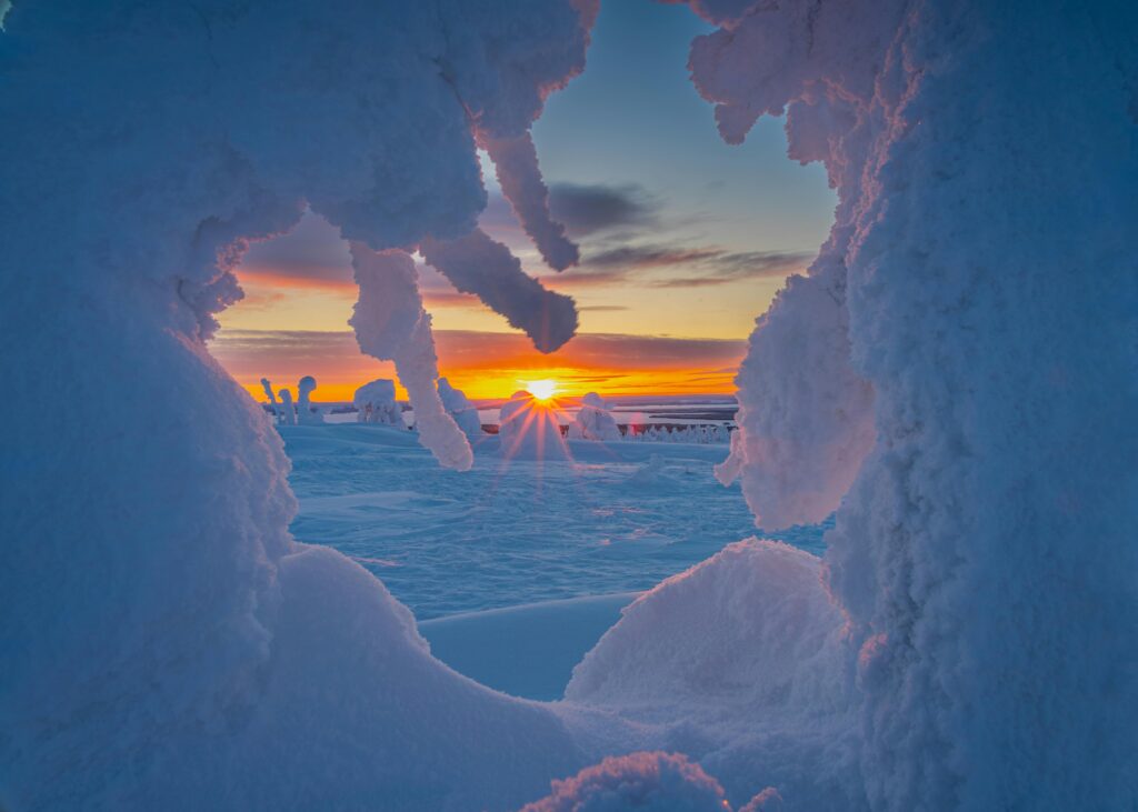 Captivating scene of a sunset viewed through icy formations in a winter wonderland.