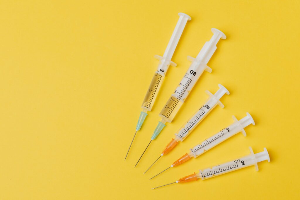 Overhead view of five syringes arranged on a yellow background.