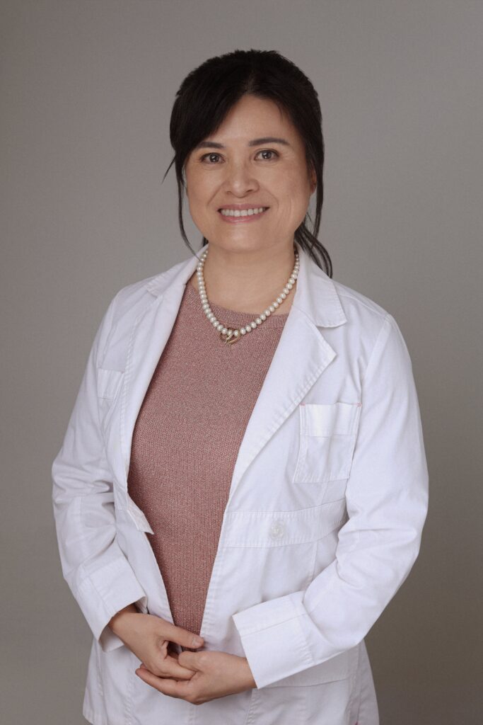A smiling healthcare professional wearing a white lab coat and a necklace, representing Friday Health.