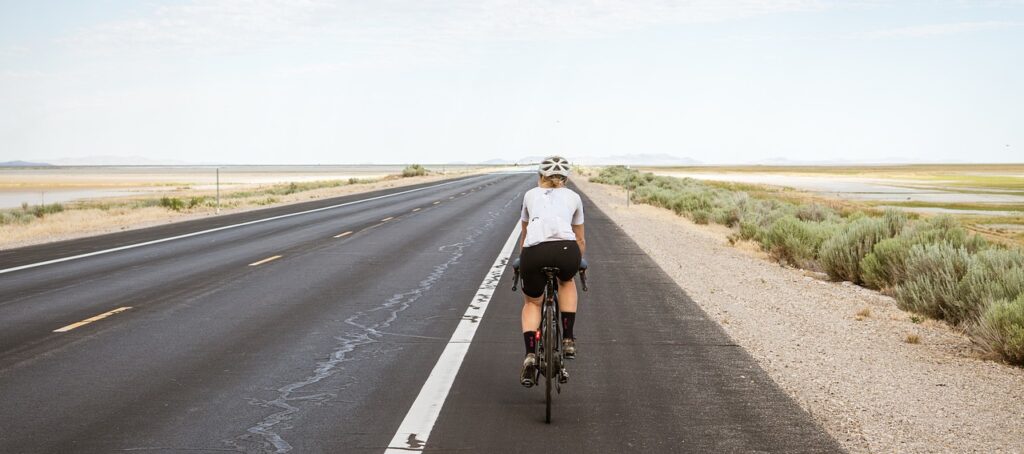 cyclist, cycling, biking, bike riding, road, pavement, highway, nature, asphalt road, desert, bike, bicycle, exercise, leisure, fitness, activity, sport, outdoors, woman
