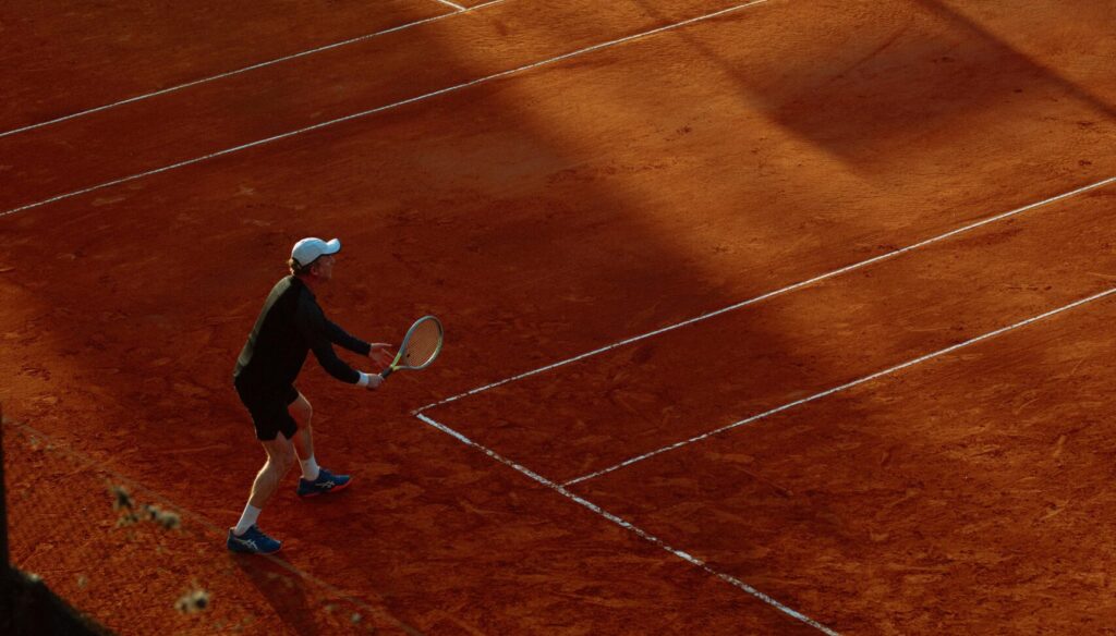 High-angle view of an active tennis game on a clay court during sunset, capturing dynamic play.