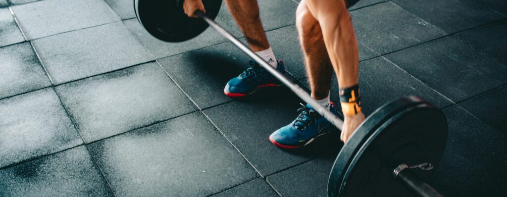 Young man lifting a heavy barbell during an intense indoor gym workout.