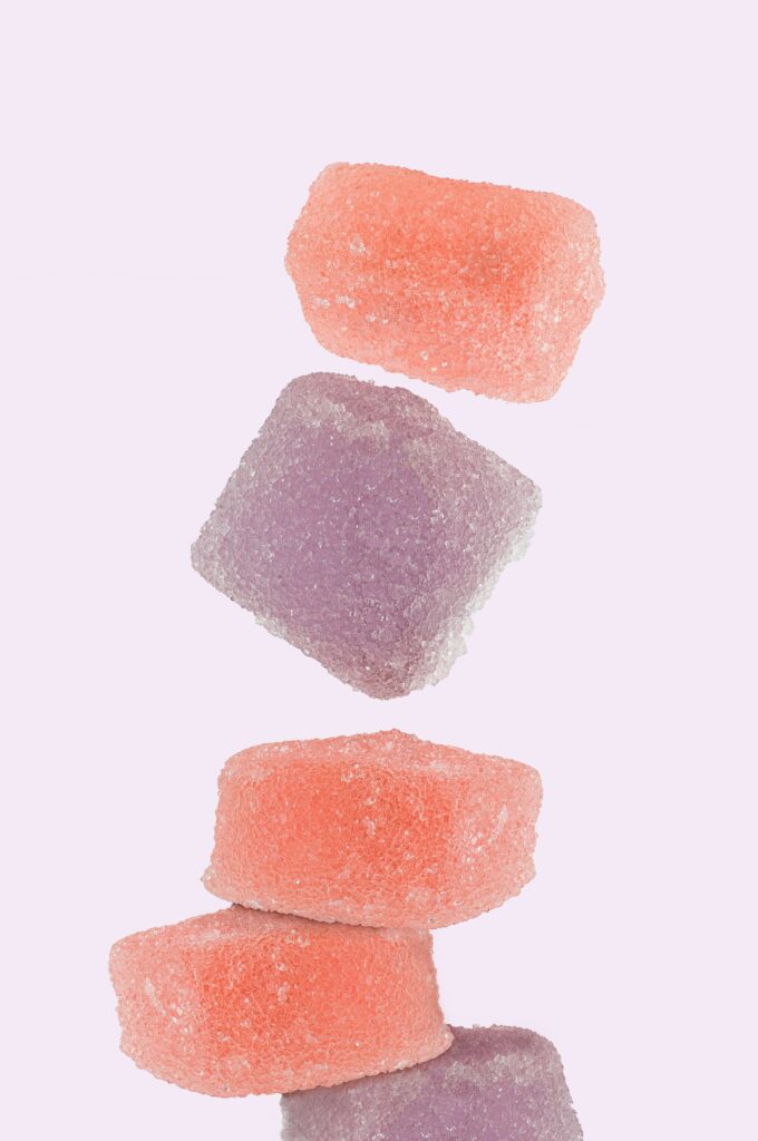 Alt text: A stack of colorful gummy squares in shades of pink and purple against a light background, representing Friday Health products.