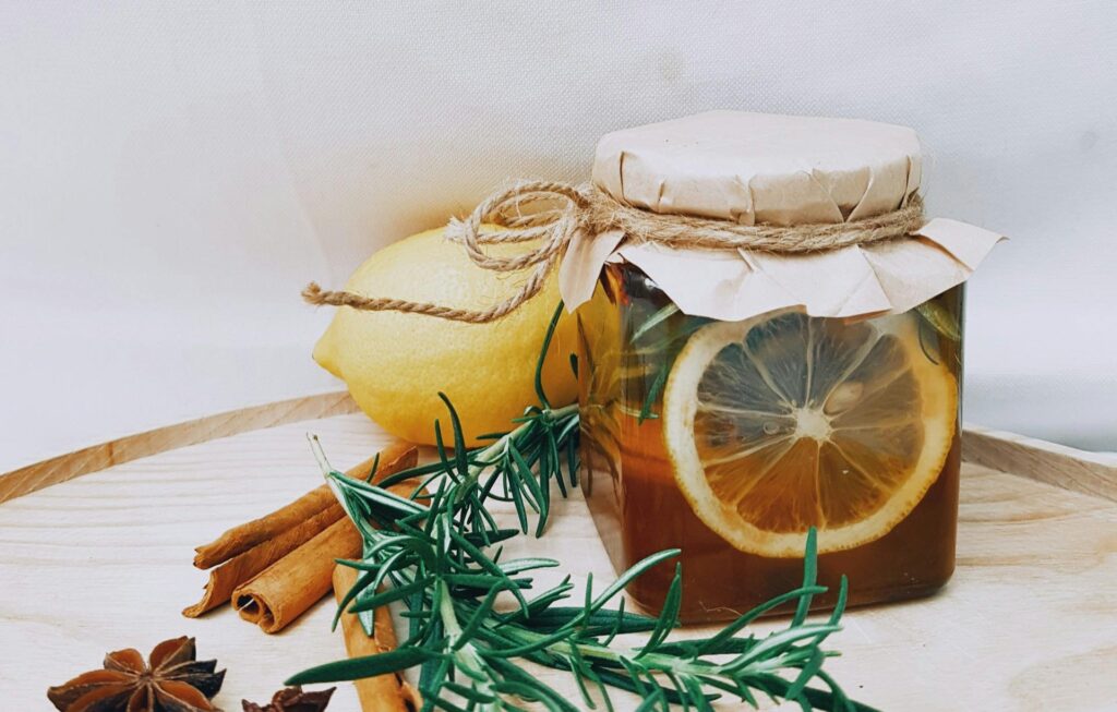 Artistic arrangement of lemon, herbs, and honey jar for DIY herbal tea.