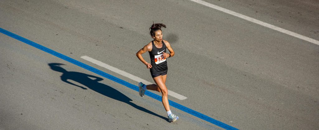 Aerial view of a woman running in a marathon on a city street, capturing endurance and athleticism.