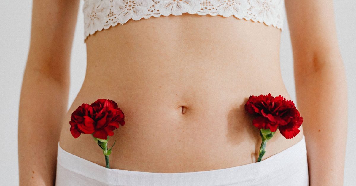 Conceptual close-up of red carnations placed on a human body in lace and underwear.